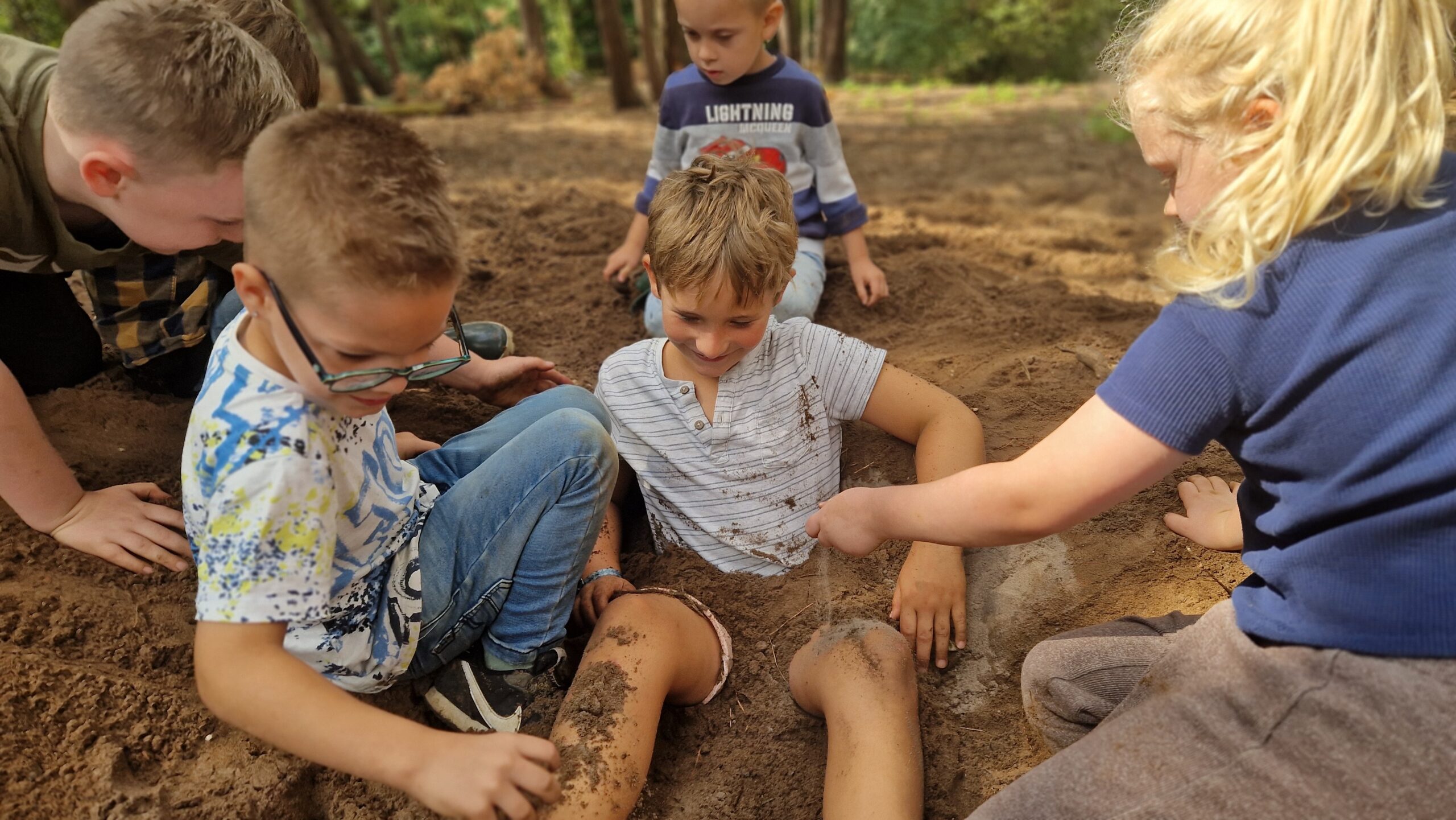 BSO-kinderen spelen samen in het zand in het bos van Terworm bij Best 4 Kids De Hoeve Heerlen