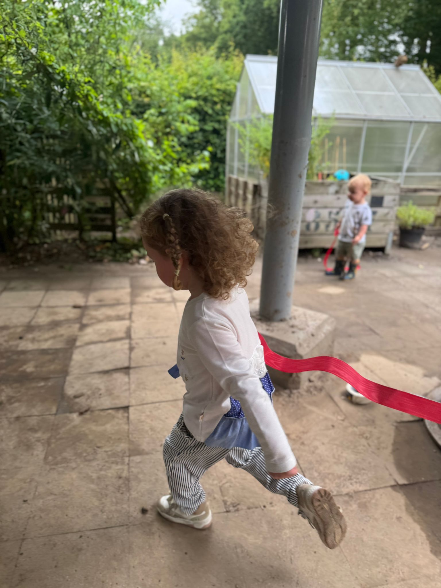 Kind speelt buiten bij de moestuin en kas van kinderopvang Best 4 Kids De Hoeve Heerlen
